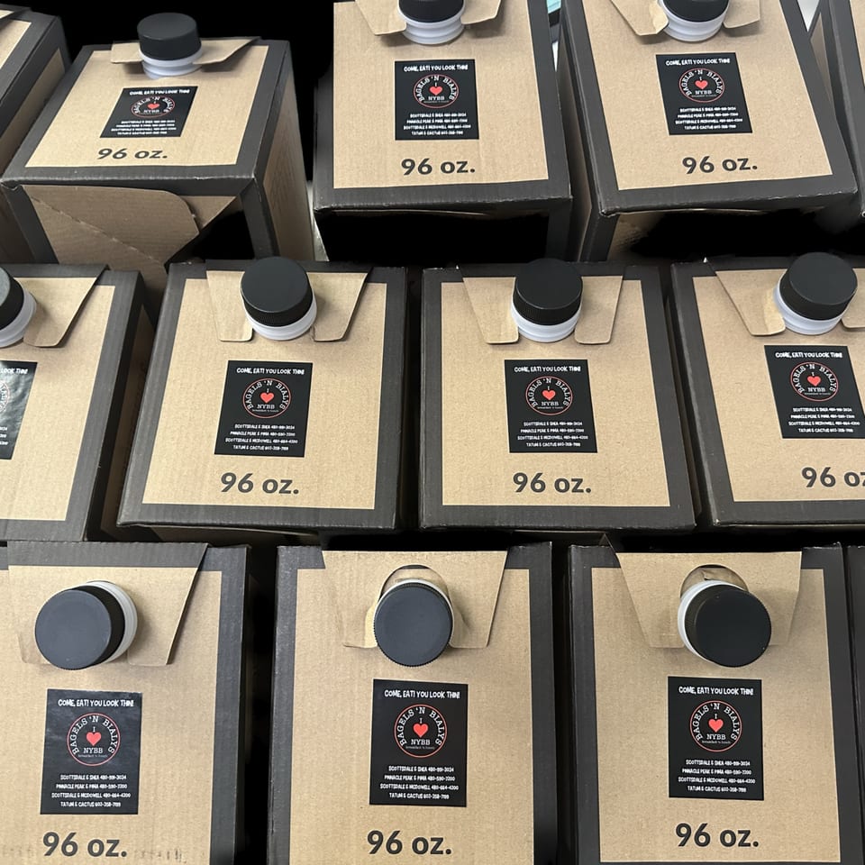 Rows of 96 oz. New York Bagels 'N Bialys branded juice cartons with black caps.