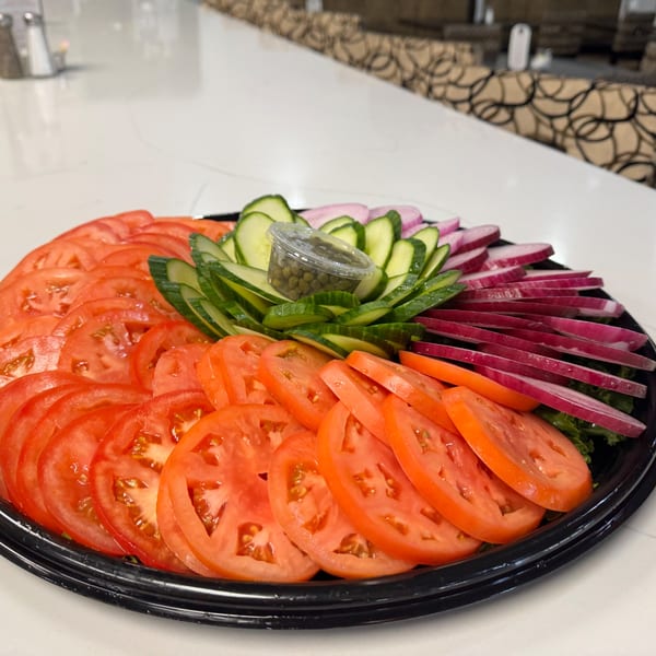 A platter of sliced tomatoes, cucumbers, red onions, and capers for bagels.