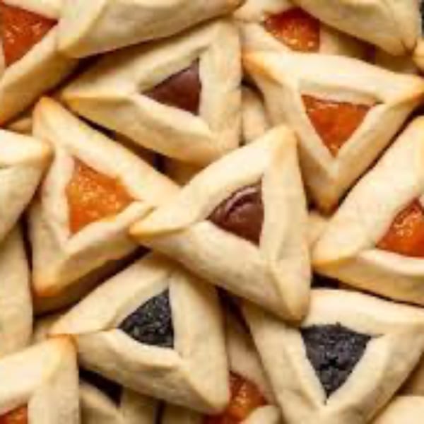A close-up of triangular hamantaschen cookies with various fruit and chocolate fillings.