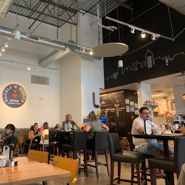 Diners seated at tables and high-top counters inside New York Bagels 'N Bialys restaurant.